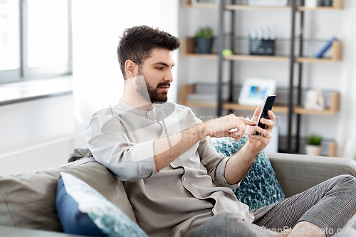 Image of young man with smartphone at home