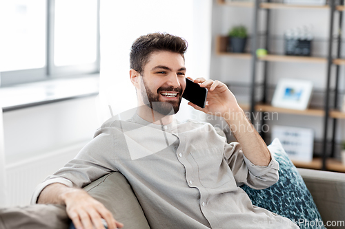 Image of happy man calling on smartphone at home