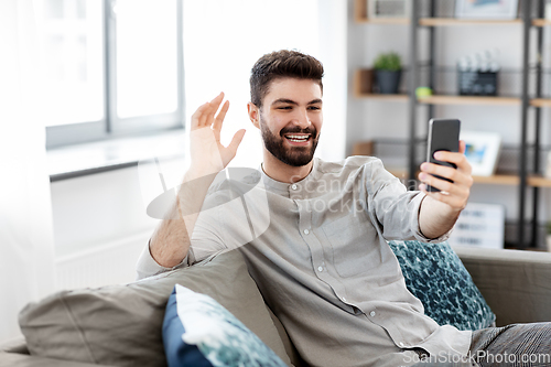 Image of man with smartphone having video call at home