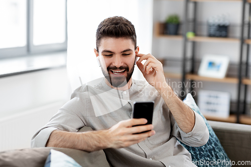 Image of man in earphones listening to music on smartphone