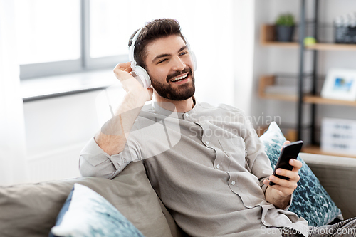Image of man in headphones listening to music on smartphone