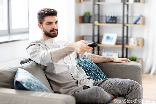 Image of man with remote control watching tv at home