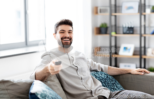 Image of happy man with remote control watching tv at home