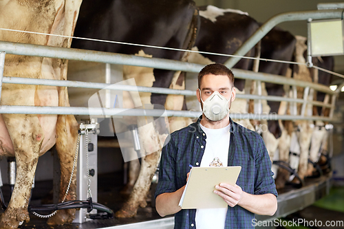 Image of man in mask with clipboard and cows on dairy farm