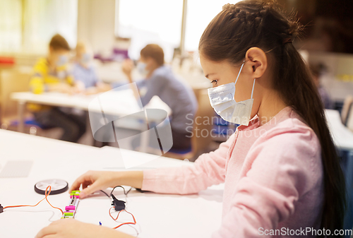 Image of girl in mask building robot at robotics school