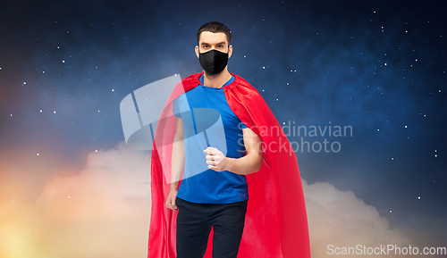 Image of man in red superhero cape and black mask at night