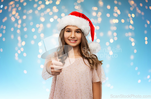 Image of happy teenage girl in santa hat showing thumbs up