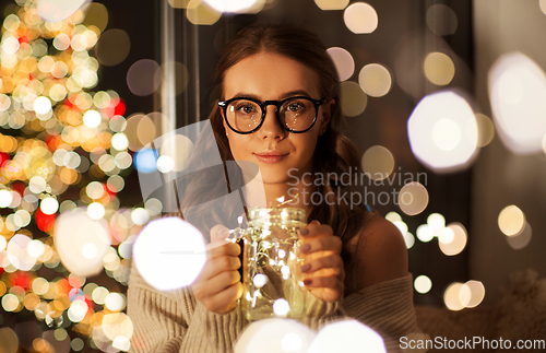 Image of woman with christmas garland lights in glass mug