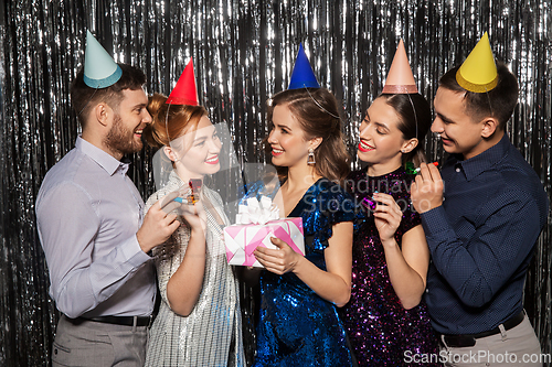 Image of happy friends in party hats with birthday gift