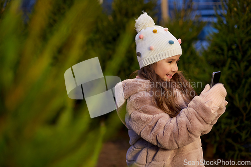 Image of girl with smartphone at christmas tree market