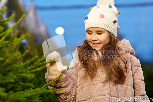 Image of little girl choosing christmas tree at market