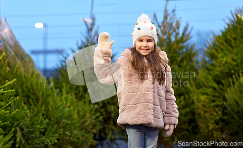 Image of little girl waving hand at christmas tree market