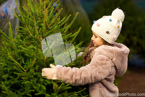 Image of little girl choosing christmas tree at market