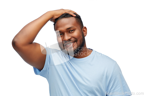 Image of smiling young african american man touching hair
