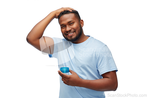 Image of african american man applying hair styling wax