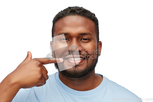 Image of smiling man pointing finger to his mouth or teeth