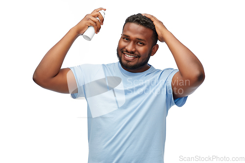 Image of african american man applying hairspray to hair