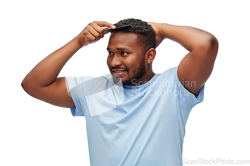 Image of happy african american man brushing hair with comb