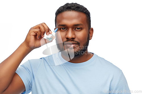 Image of young african american man using eye drops