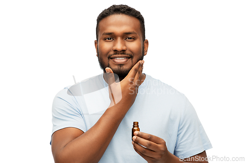 Image of african man applying grooming oil to beard