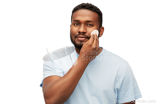 Image of african american man cleaning face with cotton pad