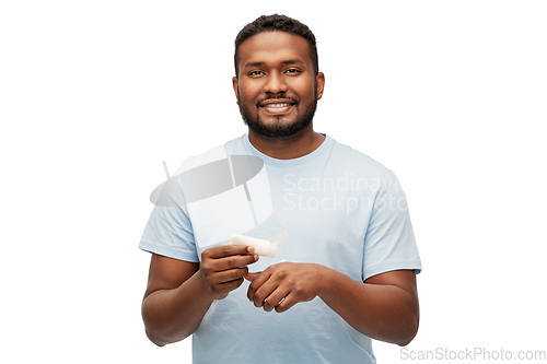 Image of happy african man applying moisturizer to his hand