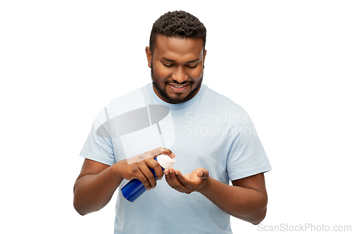 Image of happy african man applying shaving foam to hand