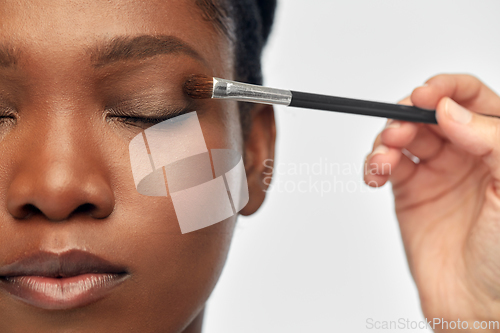 Image of face of african woman and hand with make up brush