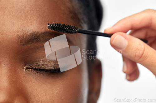 Image of face of african woman and hand with mascara brush