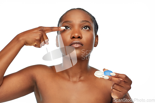 Image of african american woman putting on contact lenses