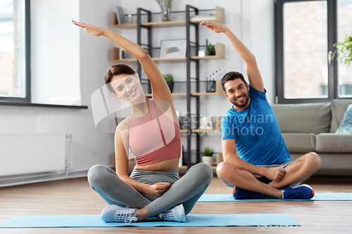 Image of happy couple exercising at home