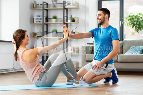 Image of woman with personal trainer doing sit ups at home