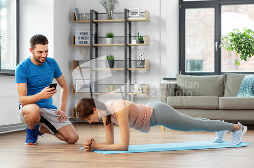 Image of woman with personal trainer doing plank at home