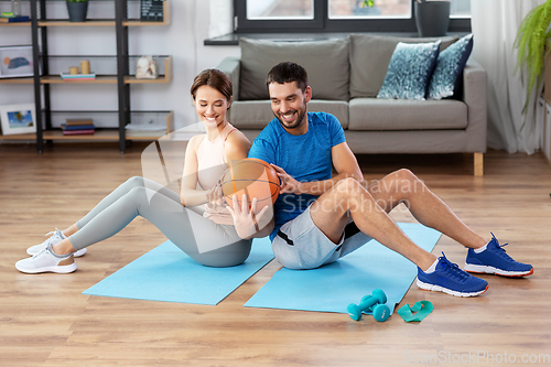 Image of happy couple exercising with ball at home