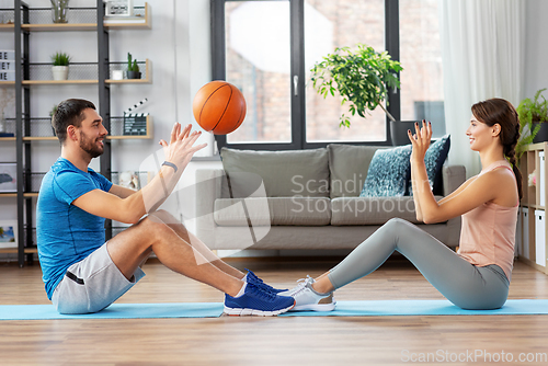 Image of happy couple exercising with ball at home