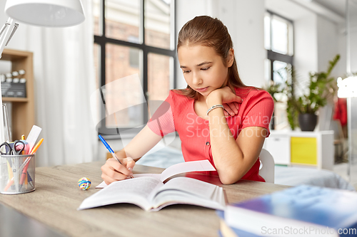 Image of student girl with book writing to notebook at home