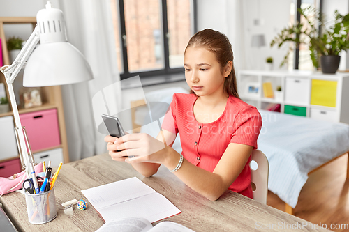 Image of girl with smartphone distracting from homework