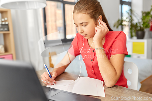 Image of student girl in earphones learning at home