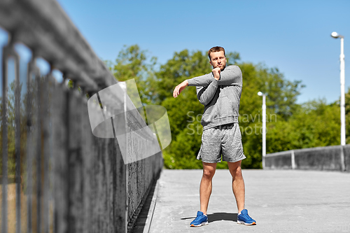 Image of man stretching hand and shoulder on bridge