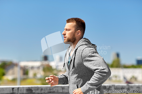 Image of happy young man running across city bridge