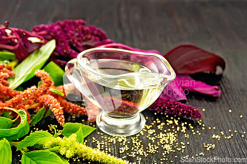 Image of Oil amaranth in gravy boat on wooden board