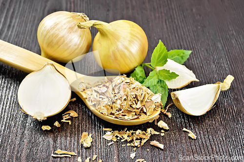 Image of Onion flakes in spoon on wooden board