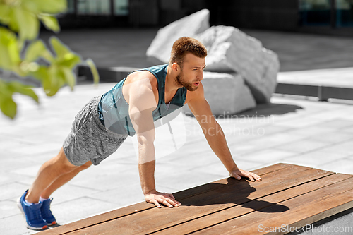 Image of young man doing push ups on city street