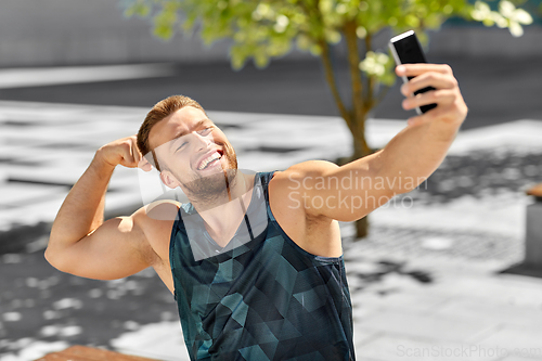 Image of man taking selfie with phone and showing bicep