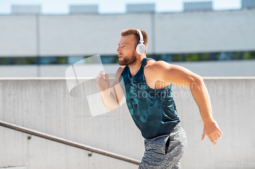 Image of young man in headphones running upstairs outdoors