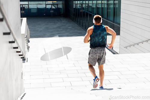 Image of young man in headphones running downstairs