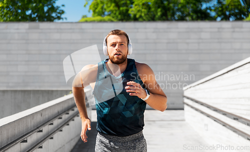 Image of young man in headphones running outdoors