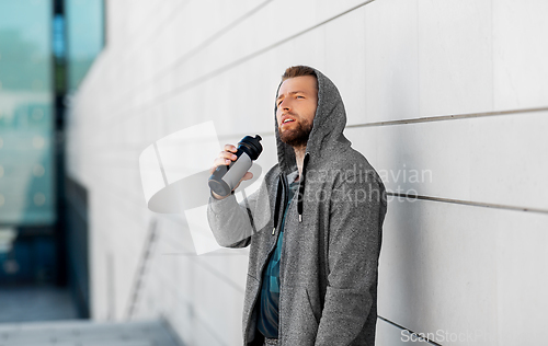 Image of sportsman with bottle of water in city