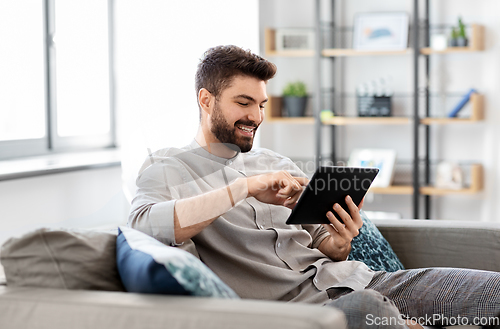 Image of smiling man with tablet computer at home
