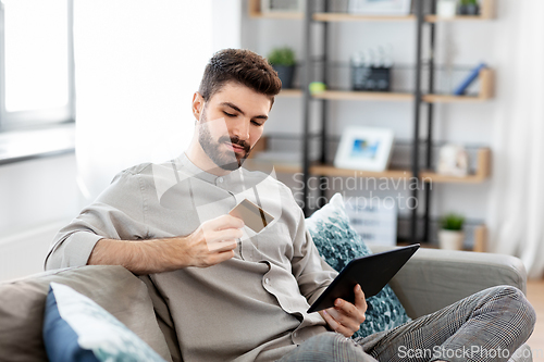 Image of man with tablet computer and credit card at home